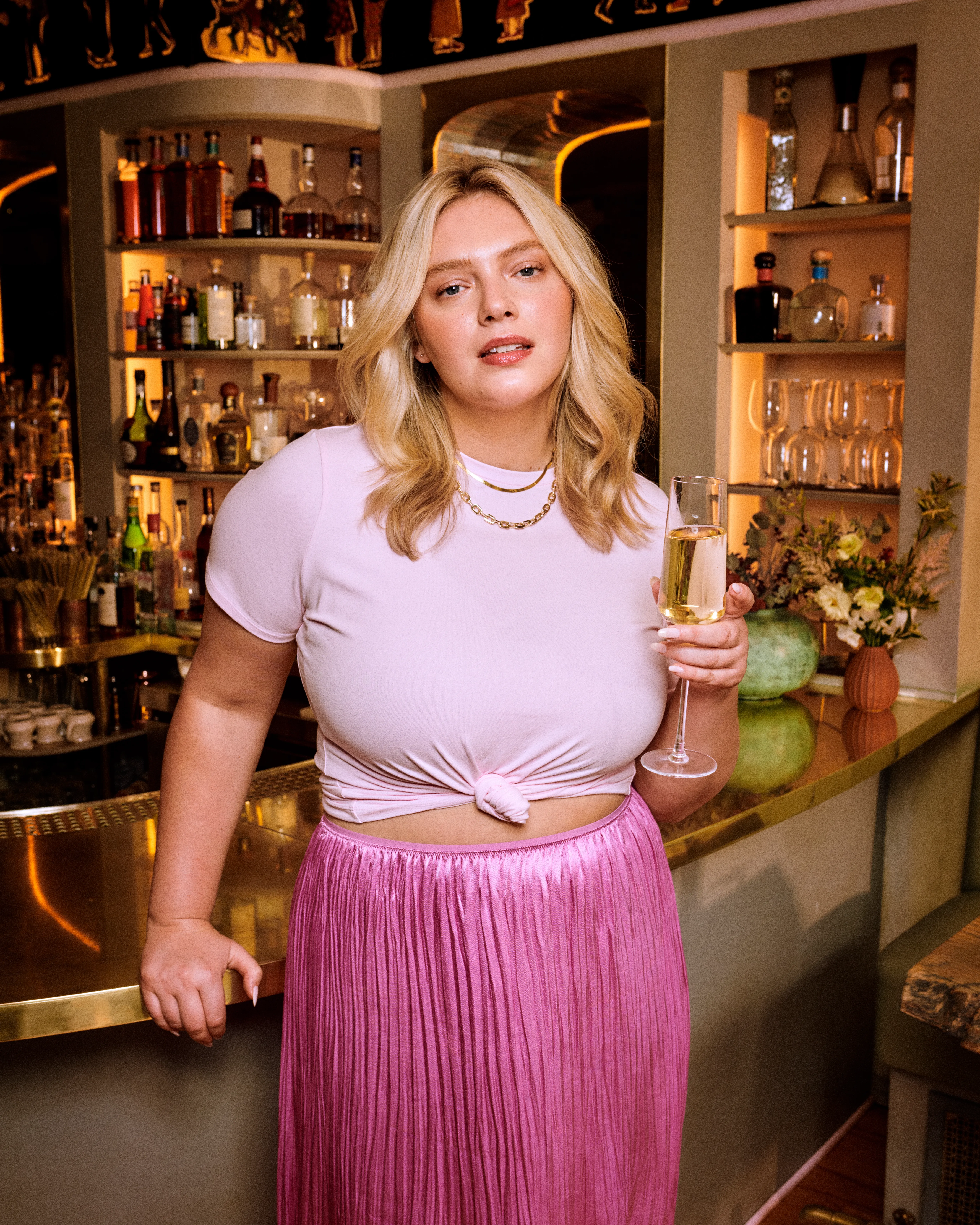 Blowouts for short hair giving a woman soft, voluminous waves as she enjoys a drink in a stylish bar setting