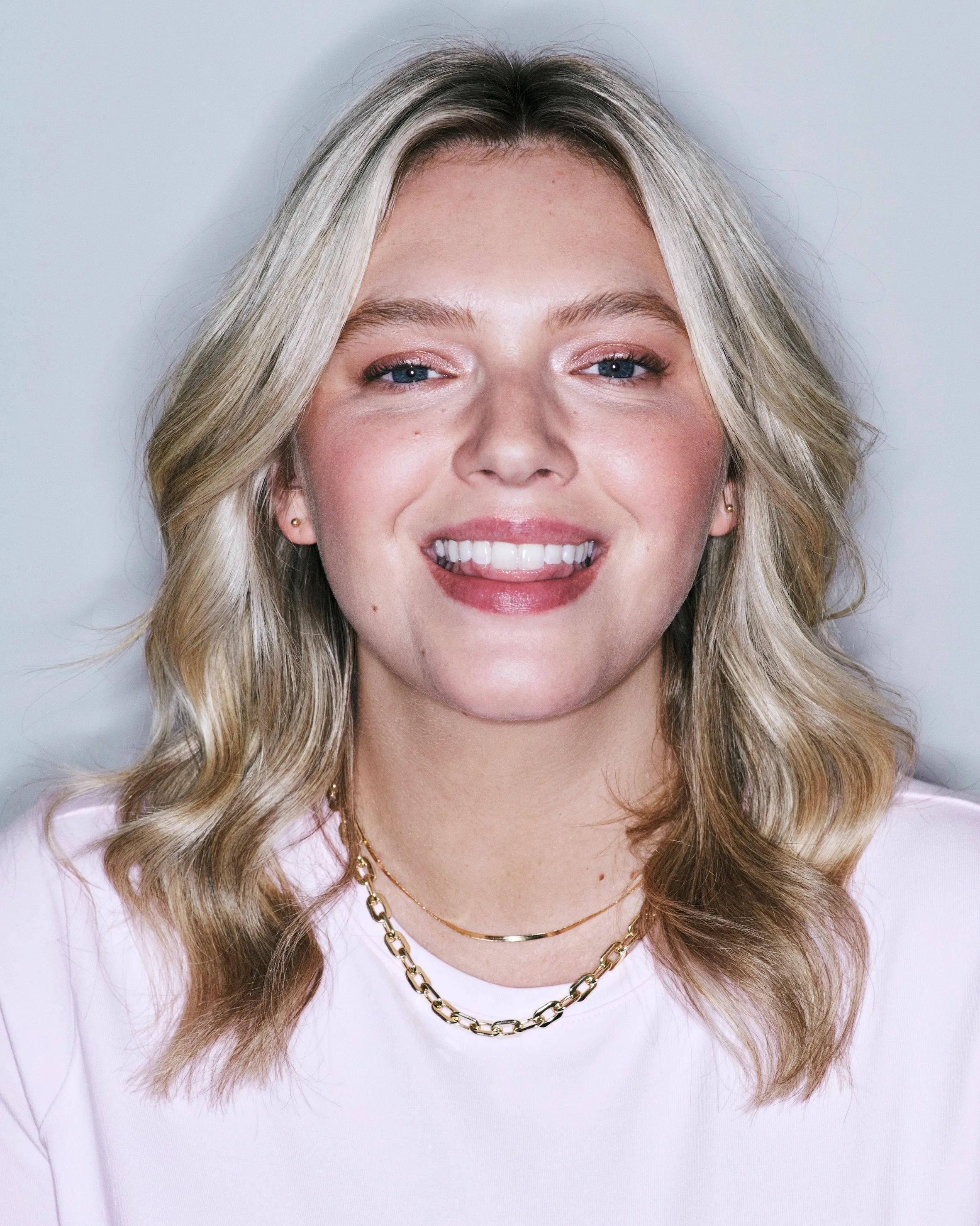 Smiling blonde woman with soft, full waves demonstrating the effect of a hair volumizer for added body.