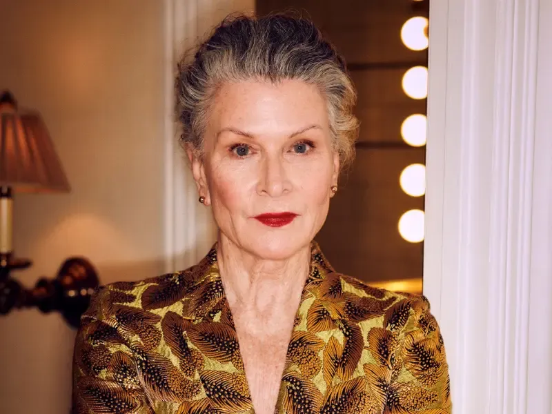 At-home glam services for mature woman in gold outfit with elegant makeup and styled gray hair.