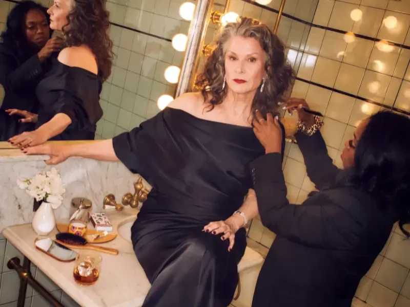 Blowouts for curly hair styling an elegant woman in an off-shoulder gown inside a glamorous vanity room