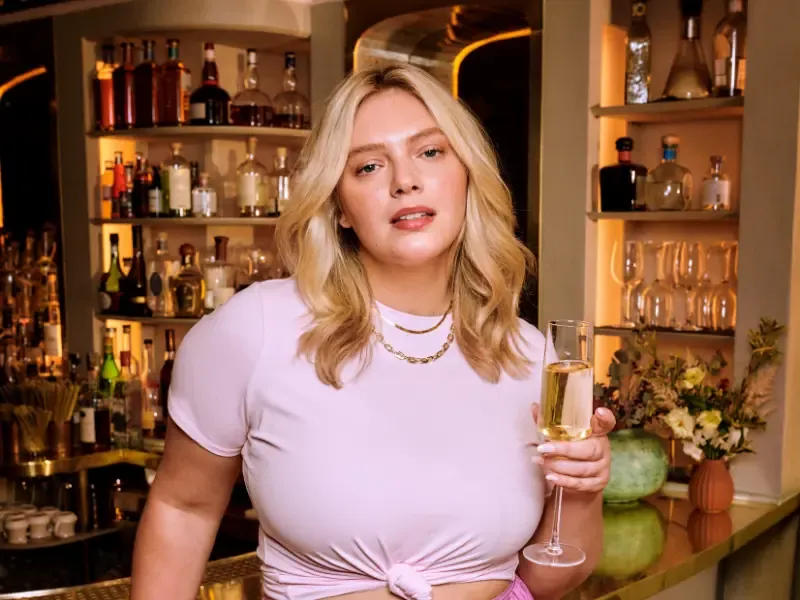 Blowouts for short hair giving a woman soft, voluminous waves as she enjoys a drink in a stylish bar setting.