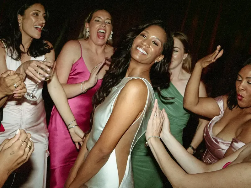 Bridal makeup artists creating radiant looks for a bride and bridesmaids celebrating and dancing together at a wedding reception.