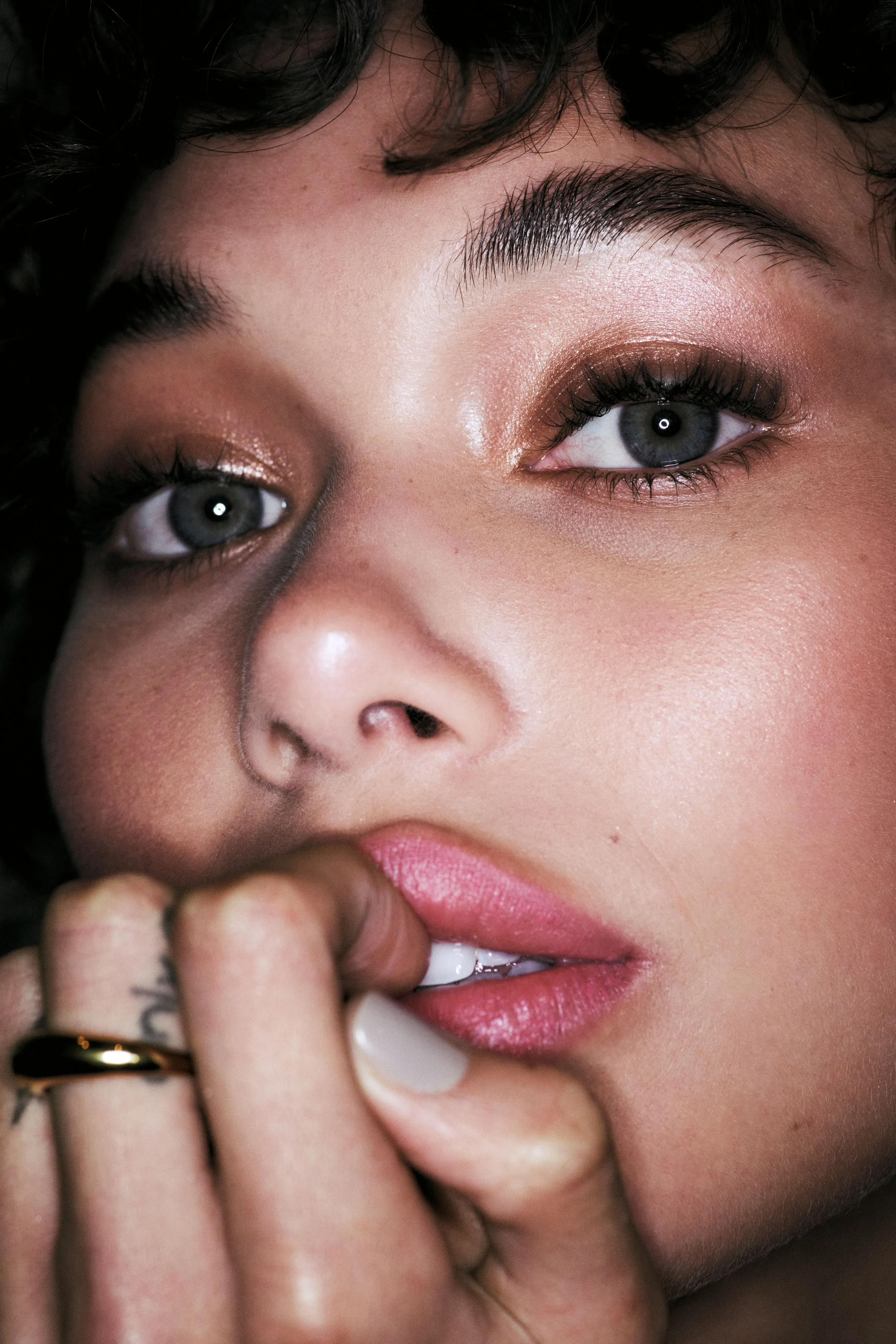 Glam services close-up of a woman with warm bronze eye makeup, fluttery lashes, glowing skin, and a rose-tinted lip.