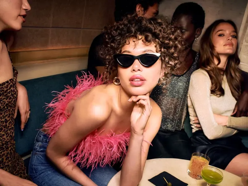 Makeup home service stylish woman with curly hair and bold makeup posing at a social gathering with friends